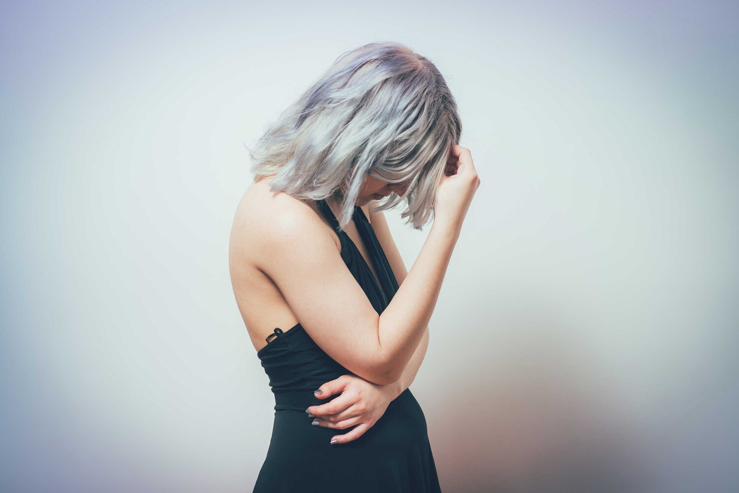 Wie kann die Befreiung von negativen Erfahrungen und Gefühlen gelingen? Eine Frau schaut nach unten und hält sich die Hand vor das Gesicht.