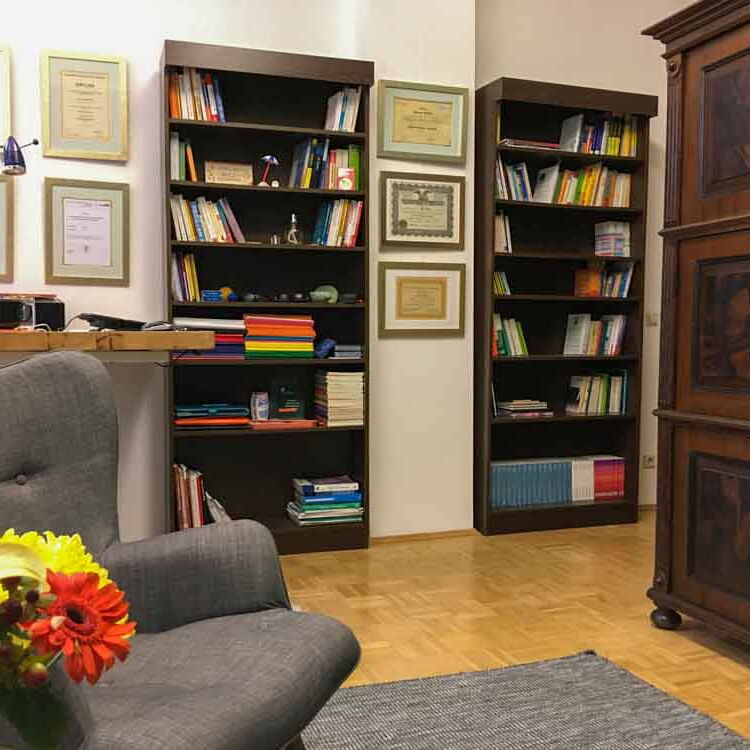 Der Behandlungsraum von Angstfreier leben mit Sessel, Bücherregalen und Schränken. An den Wänden hängen die Zertifikate von Reiner Müller.