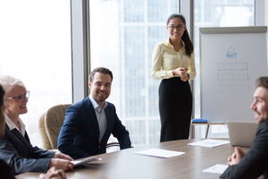 Eine Frau steht vor einer Businessgruppe und präsentiert ihre Ideen.