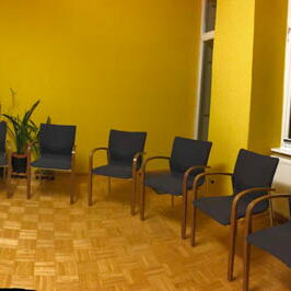 Der große Raum der Coachingpraxis mit Kreisbestuhlung und Flipchart in einer Weitwinkelaufnahme.