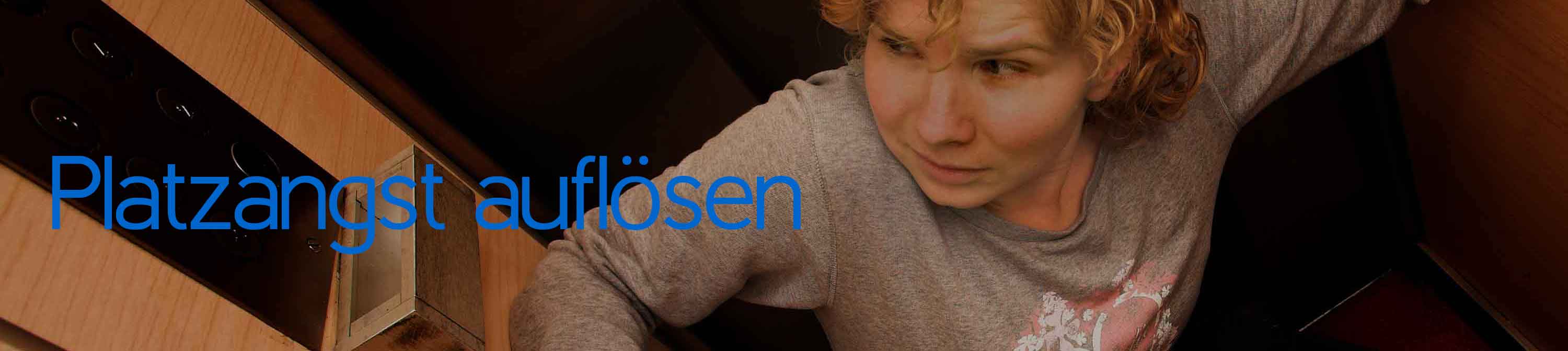 Eine Frau steht ängstlich in einem Fahrstuhl. Sie hat Platzangst.