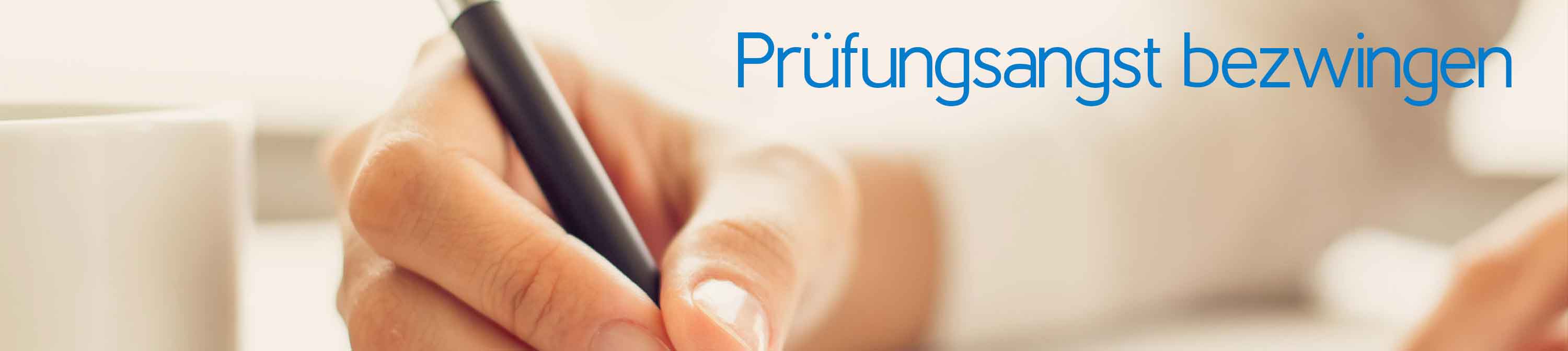 Prüfungsangst bezwingen. Eine schreibende Frauenhand auf einem Blatt. Daneben steht eine Tasse. Prüfungsangst verschiedene Ursachen haben und zum Vermeidungsverhalten führen.